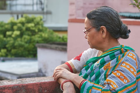 Photo of a simple looking aged Bengali woman with saddened look on a Kolkata rooftop